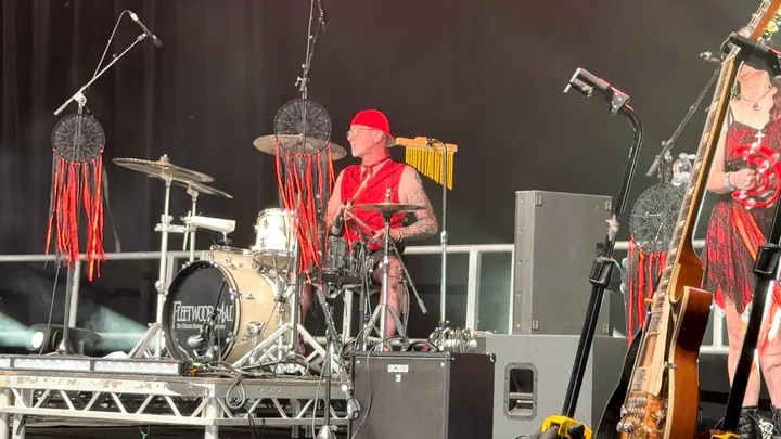 Fleetwood Mad Fleetwood Mac tribute band gallery: drummer in a red hat playing on an outdoor stage beside a singer