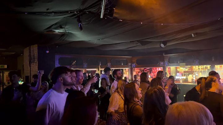 People dancing and watching the live music inside a busy venue