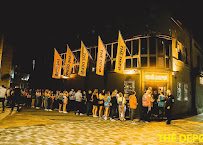 Night-time exterior of a music venue with people gathered outside and illuminated yellow signage